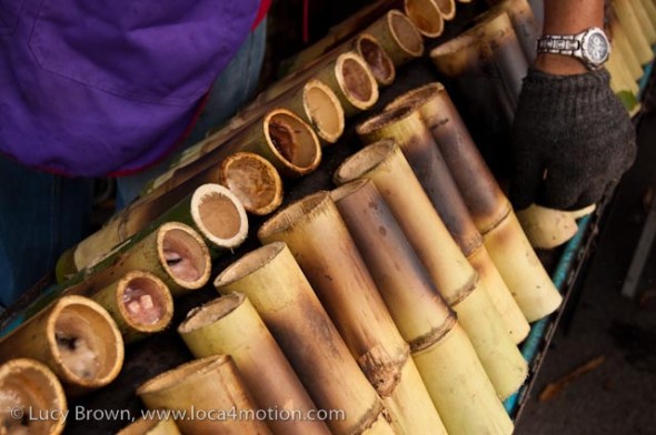 Pieces of bamboo filled with khao lam (a mixture of sticky rice, coconut milk, black beans and taro root) cooking over charcoal at a street stall, desserts, Thailand