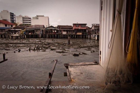 View of next jetty at low tide during storm with fishing nets hanging in foreground, Clan Jetties, George Town, Penang, Malaysia