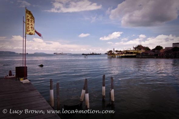 Chinese offerings and flag at end of jetty with view of Chinese temple on next jetty, Lee Jetty, Clan Jetties, George Town, Penang, Malaysia