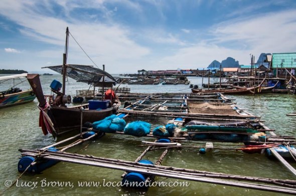 Fishing long-tail boat moored off floating raft with fish traps, Koh Panyee (Ko Panyi), Phang Nga Bay, Thailand